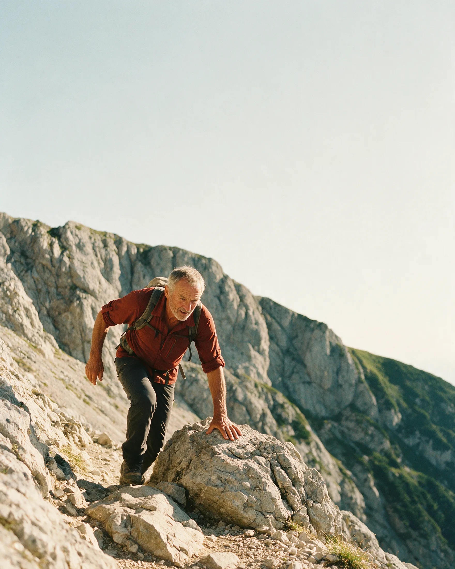 Ein Mann um die 70 klettert über einen felsigen alpinen Steig aufwärts
