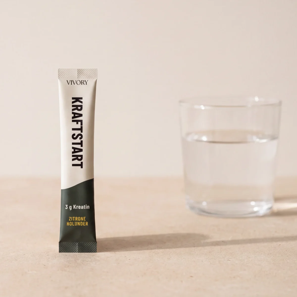 Konzeptvisualisierung: ein einzelner VIVORY-Kreatin-Stick steht neben einem Glas Wasser